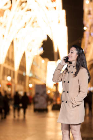 Beautiful woman talking by phone with a christmas background at Larios street in Malaga, Spainの写真素材