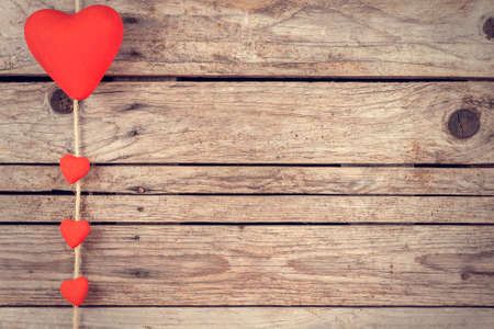 Red heart hanging on a rope over wooden backgroundの写真素材