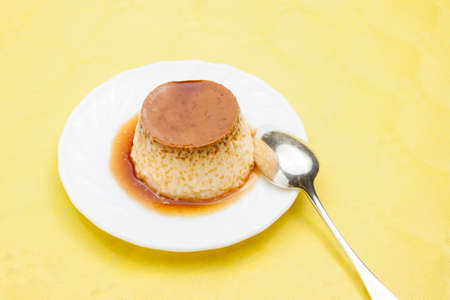 Closeup of vanilla flan with caramel on yellow tableの写真素材