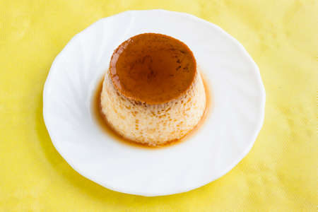 Closeup of vanilla flan with caramel on yellow tableの写真素材