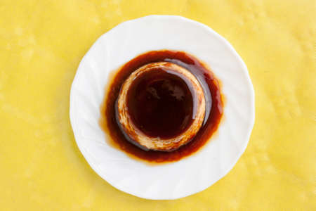 Closeup of vanilla flan with caramel on yellow tableの写真素材