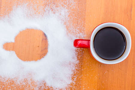 Red cup with coffee and cup footprint in sugarの写真素材