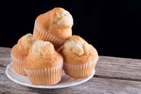 Closeup of fresh homemade cupcakes on a wooden table and black background