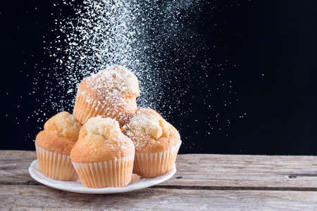 Pouring sugar on fresh homemade cupcakes with black backgroundの写真素材