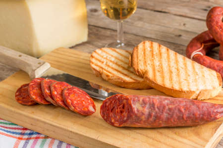 spanish tapa for brunch. Iberian chorizo, mature cheese, toasts, oil and white wineの写真素材
