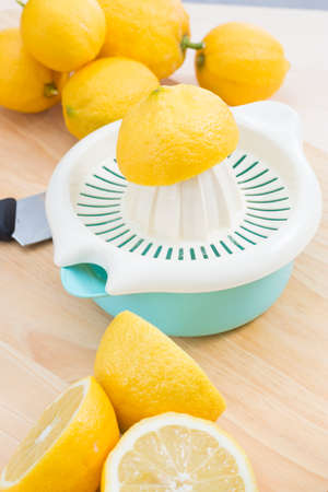 Squeezing fresh natural lemons with manual squeezer on wooden table. Making lemonadeの写真素材