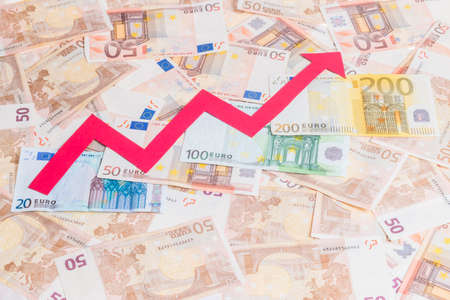 Concept of increase of euro value with red arrow growing over notes backgroundの写真素材