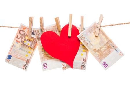Price of love concept. Red paper heart hanging with fifty euro notes isolated on white backgroundの写真素材