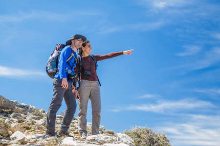 Young adult couple hiker pointing at the mountainsの写真素材