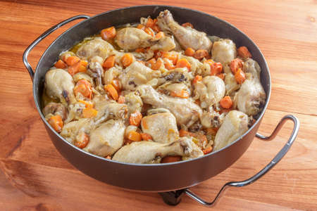 Chicken with carrots stew in a big pan on wooden tableの写真素材