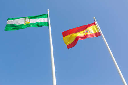 Andalusian and Spain flags with blue sky backgroundの写真素材