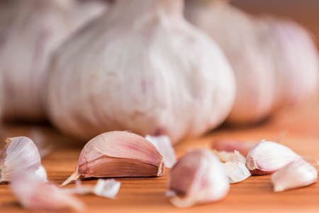 Horizontal close-up studio shot of wooden table and cloves and bulbs of garlic on itの写真素材