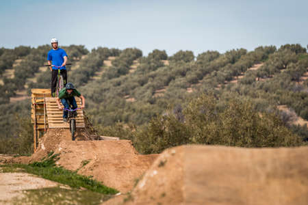 Sportive people riding bicycles on the hills and preparing to perform tricksの写真素材