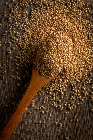 From above shot of wooden spoon with spilled aromatic seeds of quinoa on tableの写真素材