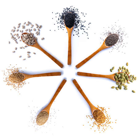 Flat lay of arranged wooden spoons with various healthy seeds in mix on white backgroundの写真素材