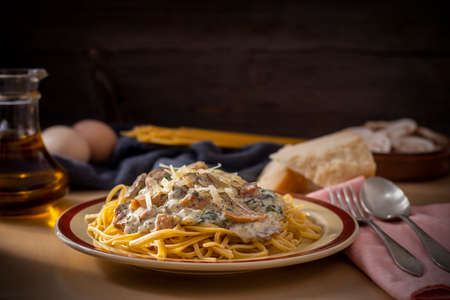Plate with pasta topped with creamy sauce and mushrooms served on table with cooking ingredientsの写真素材