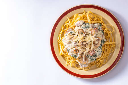 From above shot of served delicious Italian pasta with creamy sauce and mushrooms on white backgroundの写真素材