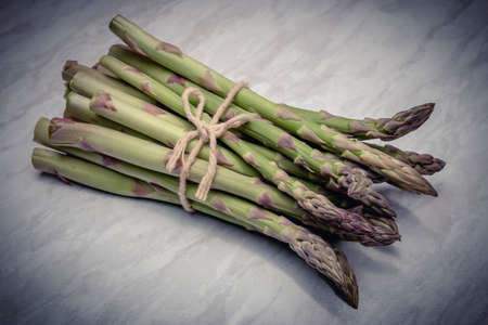 From above of green asparagus composed in heap and tied with craft string on worktopの写真素材