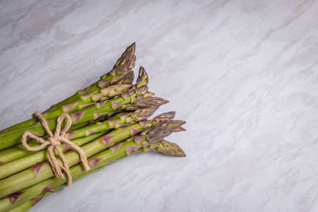 From above of green asparagus composed in heap and tied with craft string on worktopの写真素材