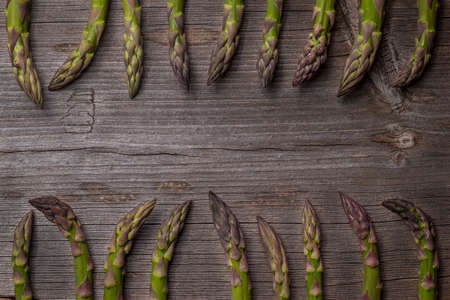 Flat lay of arranged green sprouts of asparagus on rustic wooden surfaceの写真素材