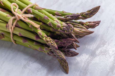 Close-up shot of green and fresh asparagus tied with string together and lying on shiny surfaceの写真素材