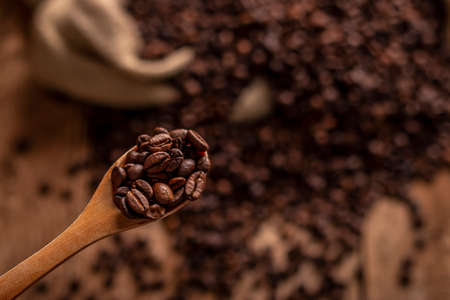 Close-up view of wooden spoon with coffee beans on blur brown backgroundの写真素材
