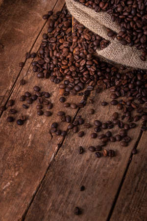 Sack of spilled fresh coffee beans on brown backgroundの写真素材