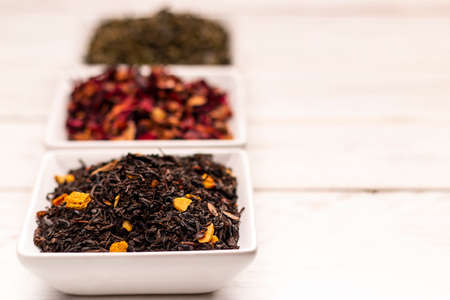 Close-up view of dry tea leaf in white scoops stand in row on white wooden tableの写真素材