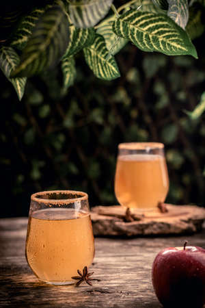 Aromatic anise lying on timber table near glass of fresh cold cider beverage