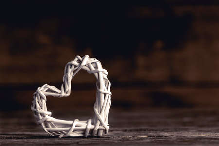 Closeup of small decorative heart made of white wicker composed on woodの写真素材