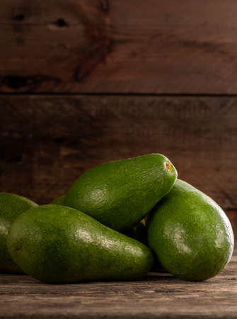 Pile of unpeeled bright green avocados on wood rustic tableの写真素材
