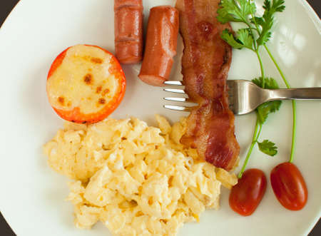 Scrambled eggs for breakfast with bacon tomatoes and parsleyの写真素材