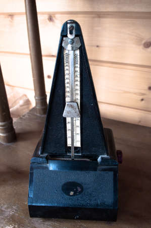 Retro black metronome on vintage wooden background
