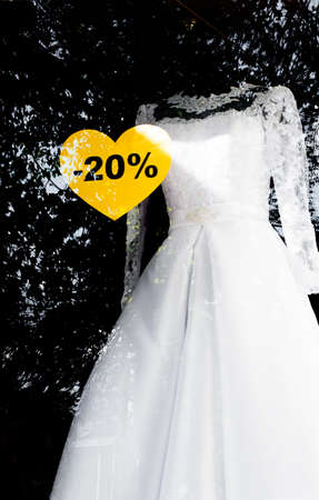 White wedding dress  with sale sign of a twenty percent discount in the windowの写真素材