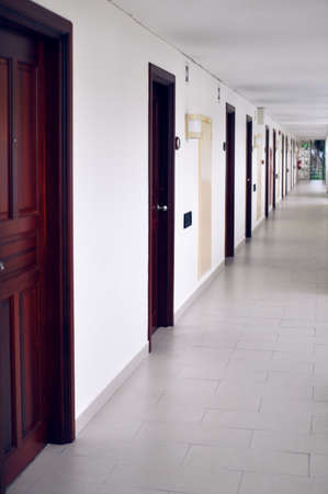 long corridor with many doors located on outdoor veranda in a cheap hotelの写真素材