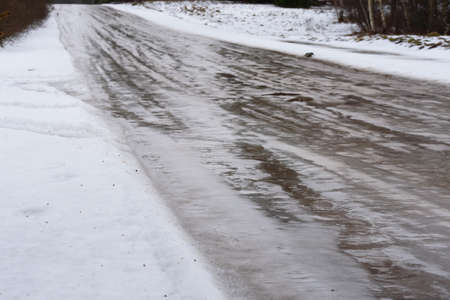 icy country road where snow on the side of the road can be seen in winterの写真素材