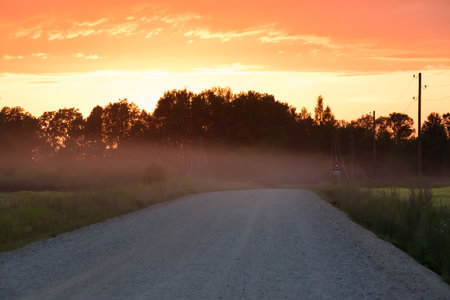 beautiful sunset on a dirt road on a summer eveningの写真素材