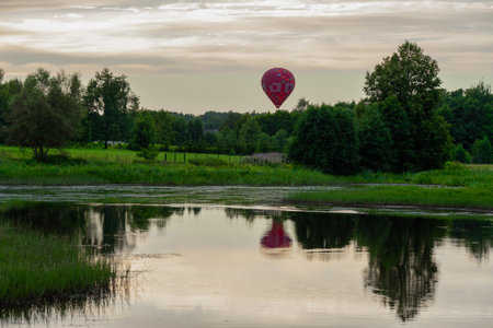 linked view in the outdoor park pond where a red hot air balloon can be seen in the distanceの写真素材