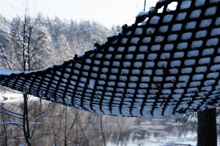 the hanging net is covered with snow in the riverbed, where trees can be seen in the distanceの写真素材