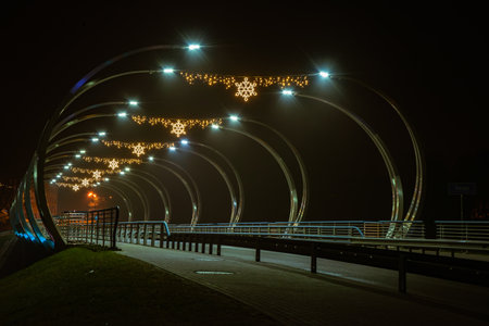 Illuminated arched bridge at night, decorated with glowing snowflakes and festive lights, creating a serene urban scene.の写真素材
