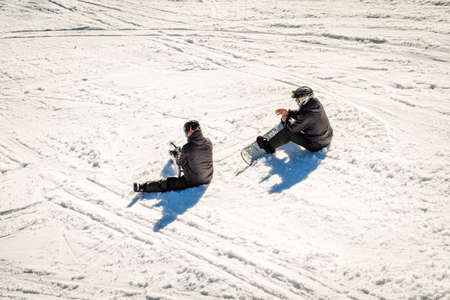 Bansko, Bulgaria - December 29, 2015: Two snowboarders are sitting on the snow and restingのeditorial素材
