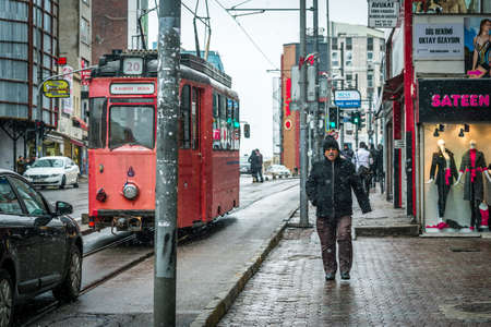 Istanbul, Turkey - January 18, 2016: Man is walking down the street in Kadikoy while red train is passing by in the snowy cold dayのeditorial素材