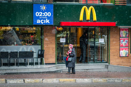Istanbul, Turkey - January 18, 2016: Old lady is passing by McDonald's in Kadikoy, Istanbul in a snowy weatherのeditorial素材