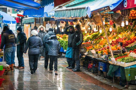 Istanbul, Turkey - January 18, 2016: People are passing by fruit sellers on kadikoy market in winter