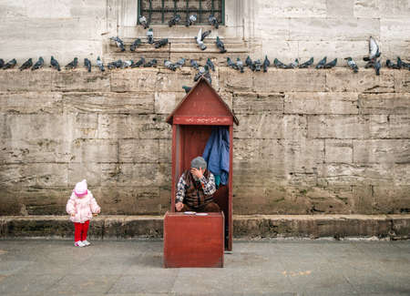 Istanbul, Turkey - January 31, 2016: Old shy man is selling grains near the New mosque Yeni camii in Istanbul, Turkeyのeditorial素材
