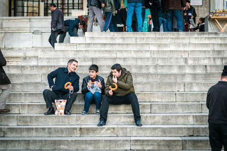 Istanbul, Turkey - January 31, 2016: Men are sitting on the stairs and eating simit in Istanbul, Turkeyのeditorial素材