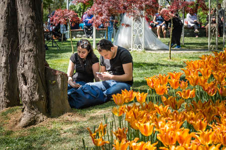Istanbul, Turkey - April 17, 2016: Couple is sitting on the grass in Emirgan park and using cellphones in Istanbul, Turkeyのeditorial素材