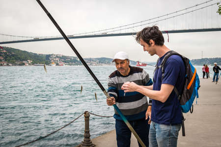 Istanbul, Turkey - April 23, 2016: Local fisherman is offering his rod to the tourist to take a photo in Istanbul, Turkeyのeditorial素材