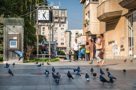 Craiova, Romania - September 16, 2016: People are walking in streets of Craiova, passing by clock and bunch of pigeons in Craiova, Romaniaのeditorial素材