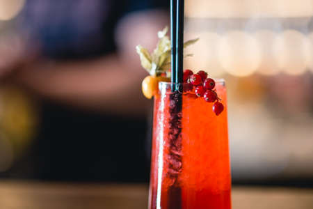 Red alcohol cocktail in the glass with berries on the bokeh background.の写真素材